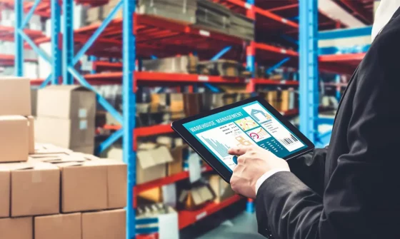 An employee using a tablet to monitor their supply chain in a warehouse.