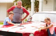 Grandfather and grandchildren with classic car